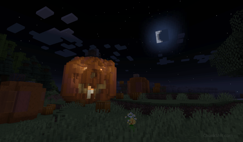 A jack-o-lantern sits in a field with smaller pumpkins around it. The moon rises in the background.
