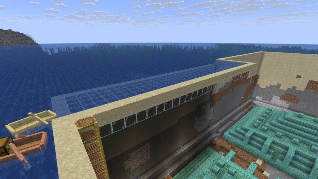 A drained ocean monument surrounded by a sand wall. A small strip of glass extends over the area with a layer of water. 