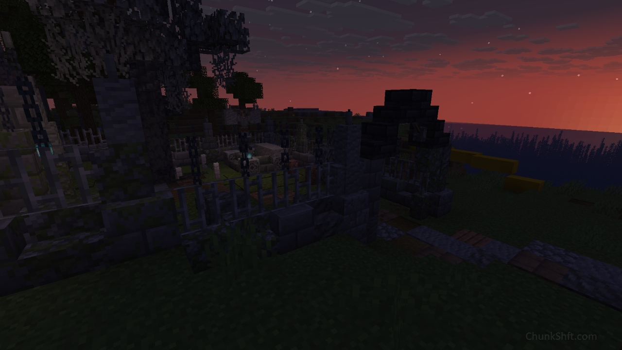 The sun sets and darkness overtakes the photo. This photo is intended to provide a day night ambience contrast for readers. A stone and iron fence surrounds the graveyard, The stone base and partitions have been weathered with moss growing on some.