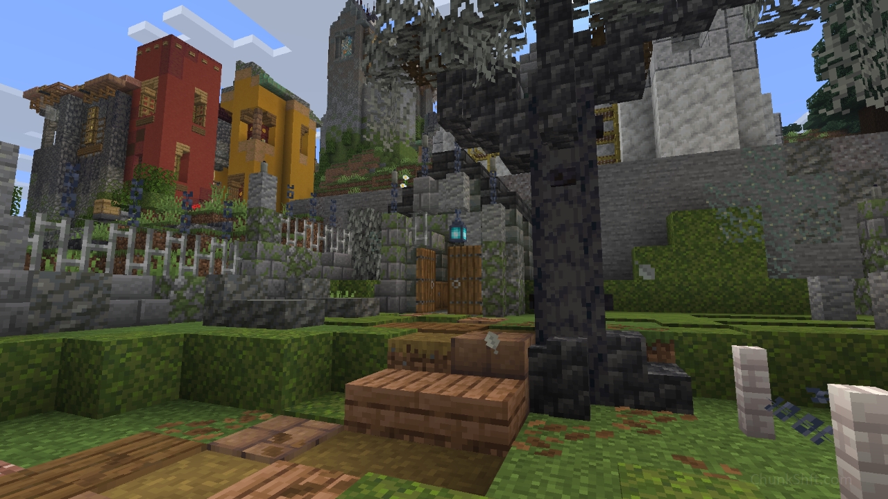 A small stone brick structure sits in the corner of the graveyard. It's exterior warn with moss growing over its surface. A path cuts through the centre of the image past the darkened trunk of a dead tree.